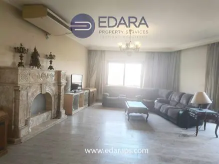 Living room featuring a marble fireplace, a gray sofa, and a wooden coffee table.