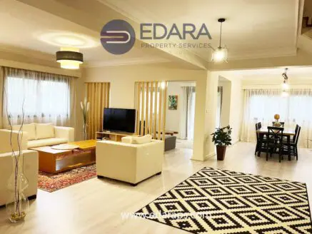 Stylish living room featuring a beige sofa, coffee table, and patterned rug in a well-lit space.