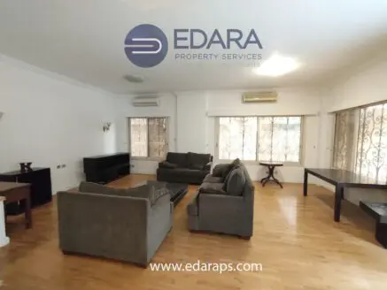 Living room featuring gray sofas, a wooden coffee table, and large windows with curtains.