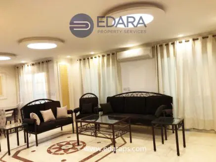 Living room featuring a black sofa set and a glass coffee table with decorative pillows.