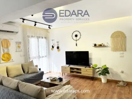Contemporary living room featuring a television, sofa, and decorative wall hangings.