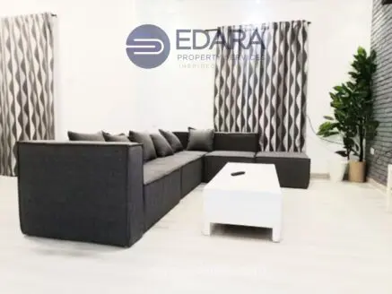 Gray sectional sofa with cushions and a white coffee table in a contemporary living room setting.