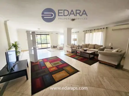 Spacious living room featuring a sofa set, coffee table, and television on a stand.