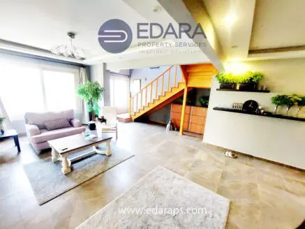 Bright living room featuring a sofa, coffee table, and a staircase with wooden accents.
