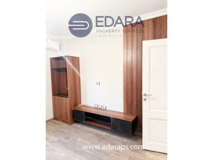 Wooden TV stand with shelves and a wall panel in a room setting.