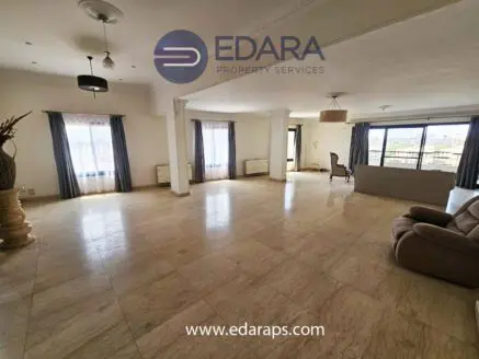 Large living room featuring marble flooring, large windows, and minimal furniture arrangement.