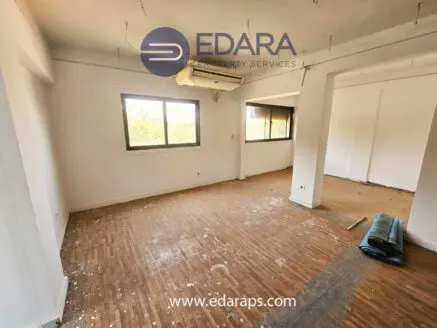 Interior view of an empty room featuring wooden flooring and two windows.
