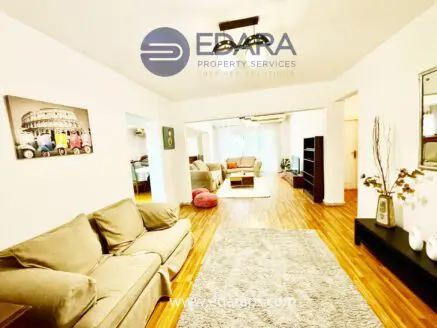 Spacious living room featuring a beige sofa, wooden flooring, and a modern decor style.