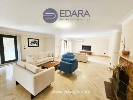 Spacious living room featuring modern white sofas, a coffee table, and a television setup.