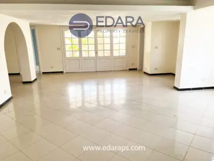 Spacious empty interior with glossy tiled floor and large windows allowing natural light.
