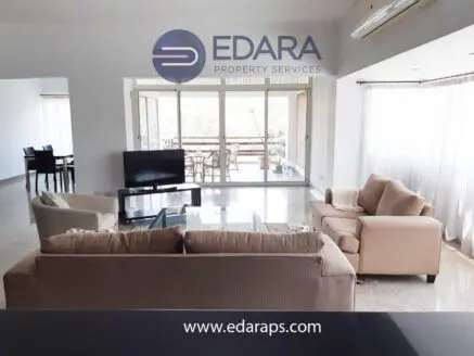 Spacious living room featuring a beige sofa set and a television in a modern interior design.