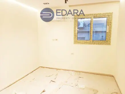 Interior view of an empty room with a window and light-colored walls, showing a partially finished floor.