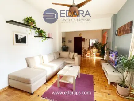 Bright living room featuring a beige sectional sofa, coffee table, and wall-mounted television.