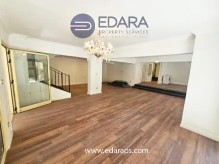 Interior view of a spacious room featuring wooden flooring and a chandelier.