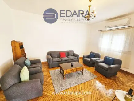 Living room featuring gray sofas, a wooden coffee table, and a chandelier in a well-lit space.