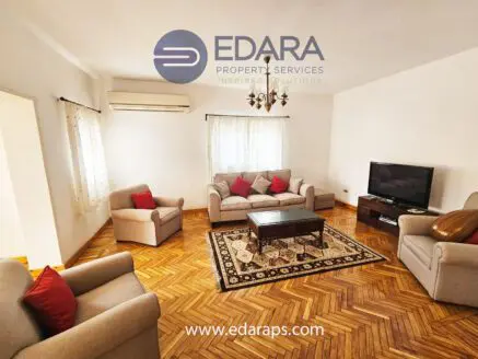 Living room featuring a sofa set with red cushions, a wooden coffee table, and a television on a stand.