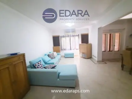 Living room featuring a light blue sofa with decorative cushions and wooden furniture.
