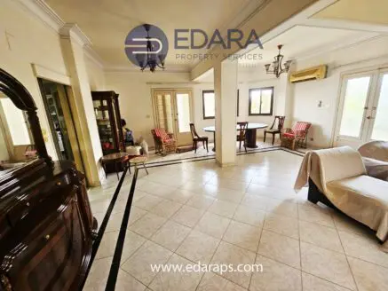 Spacious living room featuring a dining area, wooden furniture, and tiled flooring.