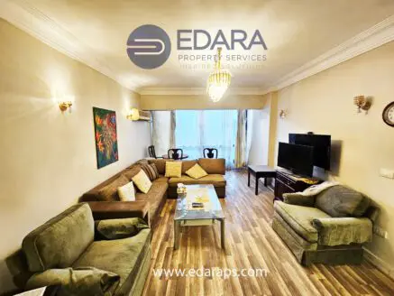 Spacious living room featuring a green sofa set, coffee table, and a television mounted on the wall.