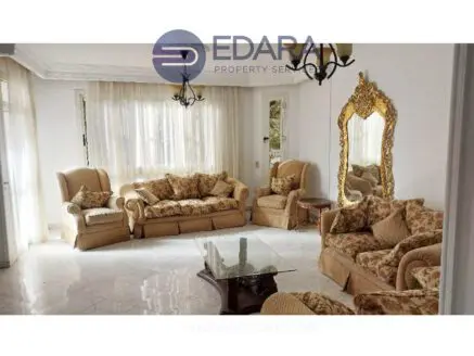 Living room featuring beige upholstered sofas and a decorative mirror on the wall.
