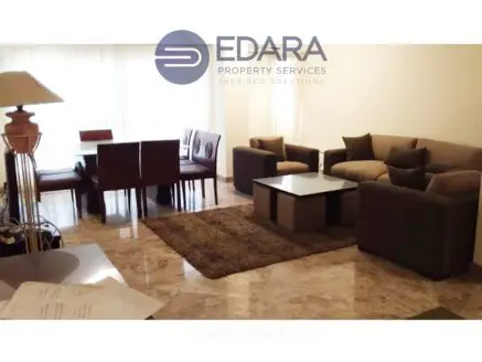 Contemporary living room with a sofa set, coffee table, and dining area featuring a glass table and wooden chairs.