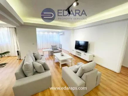 Contemporary living room featuring a light gray sofa set and a flat-screen TV on a white cabinet.