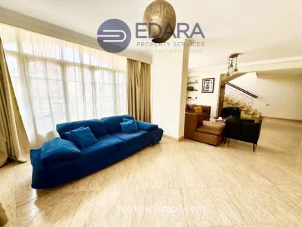 Living room featuring a blue sofa, large windows, and beige marble flooring in a modern interior design.