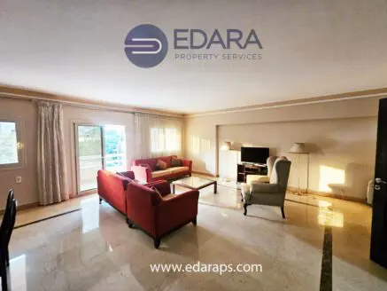 Spacious living room featuring a red sofa set and a television on a stand.