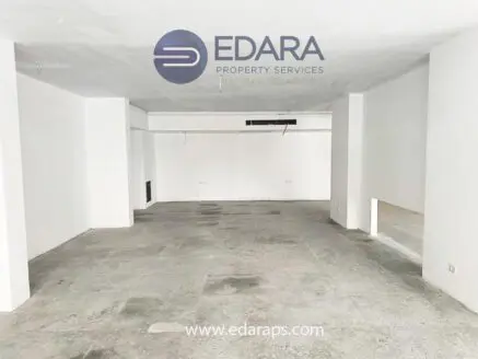Empty commercial space with white walls and concrete flooring, featuring minimal interior elements.