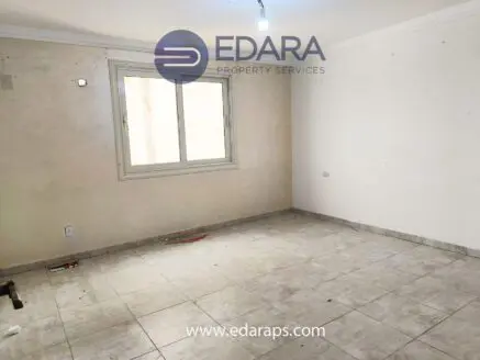 An empty room featuring a window and tiled flooring, with a light fixture on the ceiling.