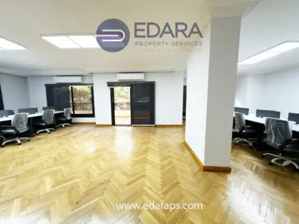 Interior view of an office space featuring desks, chairs, and wooden flooring.
