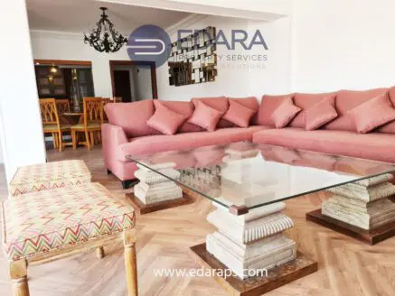 Living room featuring a pink sectional sofa with cushions and a glass coffee table on decorative stone bases.