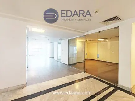 Interior view of an office space featuring glass partitions and tiled flooring.