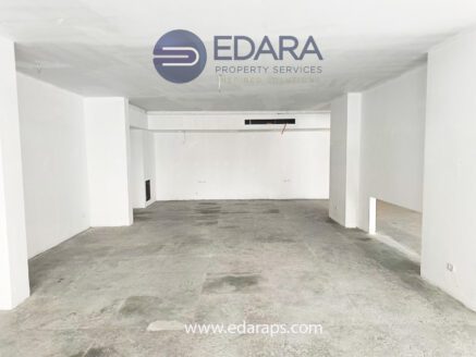 Empty commercial space with white walls and concrete flooring, featuring minimal interior elements.