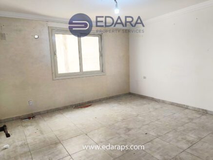 An empty room featuring a window and tiled flooring, with a light fixture on the ceiling.