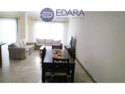 Interior view of a living room featuring a sofa, dining table, and television.