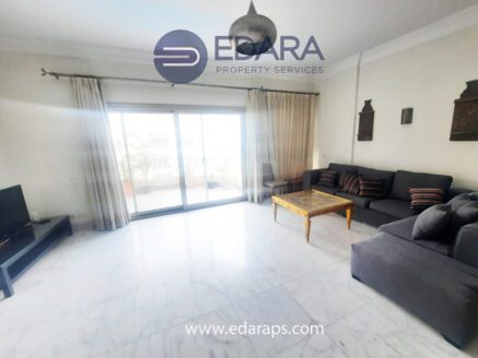 Spacious living room featuring a gray sofa, wooden coffee table, and large windows with curtains.